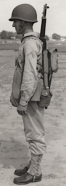 U.S. Army photograph published 13 August 1941 showing the khaki cotton field uniform outfitted for the combat role.  The soldier dons the new M‐1 steel helmet, leggings, gas mask carrier, and full field pack.  By mid‐1942, the khaki cotton uniform would be supplanted by the two‐piece herringbone twill uniform for use as a hot weather combat uniform.