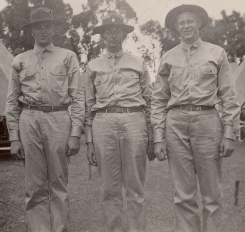 Soldiers stationed in Oahu, Hawaii in 1942 wearing khaki cotton uniforms with olive‐drab service hats.  The service hat was difficult to store and maintain and was phased out in favor of the khaki cotton field hat and fiber helmet.  Eventually, all three types of headgear were replaced by the M‐1 helmet liner for light field use.  This hat is often referred to as a Campaign Hat.  Enlisted men sometimes wore distinctive unit insignia, or the service cap badge attached to the front vent hole.