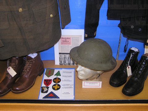 View of Niles Public Library "Service Uniforms of World War II" 2011 Memorial Day display showing M-1 helmet, U.S. Army rough-out composition sole service shoes, and U.S. Navy field shoes.