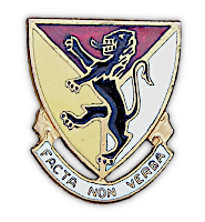 Close‐up view of the distinctive unit insignia of the 124th Field Artillery Regiment worn on the lapels of the service coat shown below and the left front of the field cap shown above. Designs for distinctive insignia had to be approved by the Adjutant General before they could be worn. Distinctive insignia could represent regiments, separate battalions, or separate companies. In this case, the 124th Field Artillery was a regiment of the 33rd Infantry Division during 1941‐42. Heraldic in design, these insignia were usually made up in enamel and were attached to the lapel by a screw post and nut.