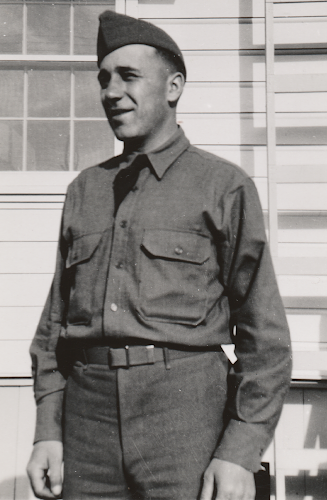 Enlisted man wearing the wool garrison uniform without coat. Per regulations the black necktie is tucked into the shirt between the second and third buttons when the coat is not worn. The soldier wears a specification 8‐108 wool shirt evidenced by the front button placket visible in the photo. Also, note the M‐1937 web waist belt and field cap.