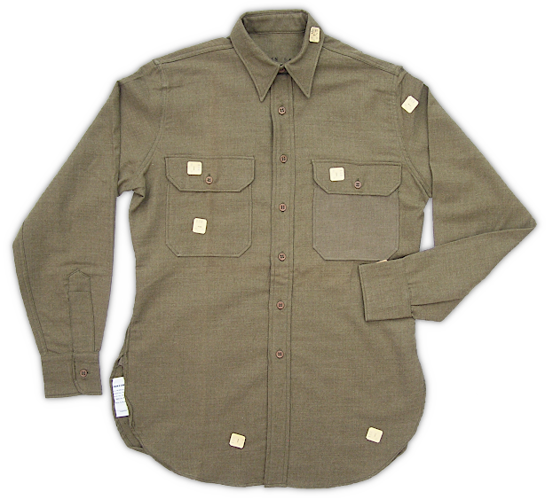 Enlisted man's flannel shirt (Shirts, Flannel, Olive‐drab, Coat-style; Specification QMC 8‐108, 2 August 1937). A dress style shirt made of wool‐cotton flannel in olive‐drab shade 31 worn with the wool service uniform in colder conditions. Both flannel and worsted shirts were cut in the same pattern and produced in tandem through 1940. By 1941, the flannel shirt became the primary shirt worn with the enlisted man's wool service uniform. The white tags attached to the front of the shirt shown above are called pin tickets (cutter's tags). They had a shade code and size printed on them to ensure garments were assembled with the correct size parts and matched in color.